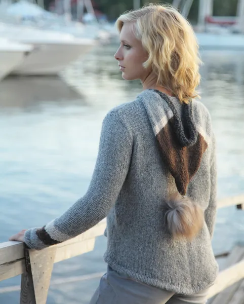 Ung kvinne står ved bryggegelender og ser inn mot båthavn og land