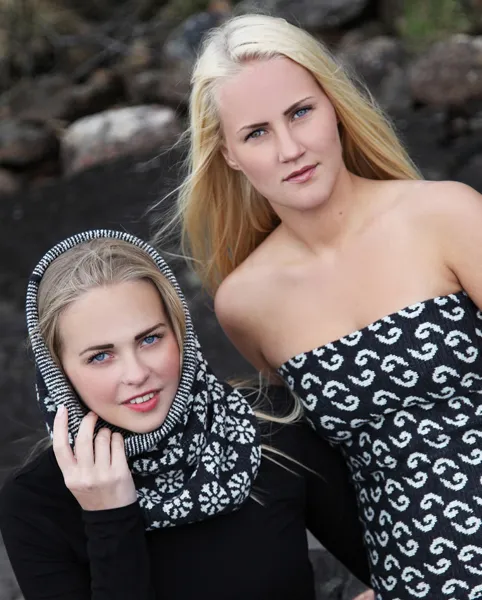 To jenter foran steinete natur mot skogen. En er ikledd mølle-mønstret hals, mens den andre er ikledd en tubetopp med krokmønster.