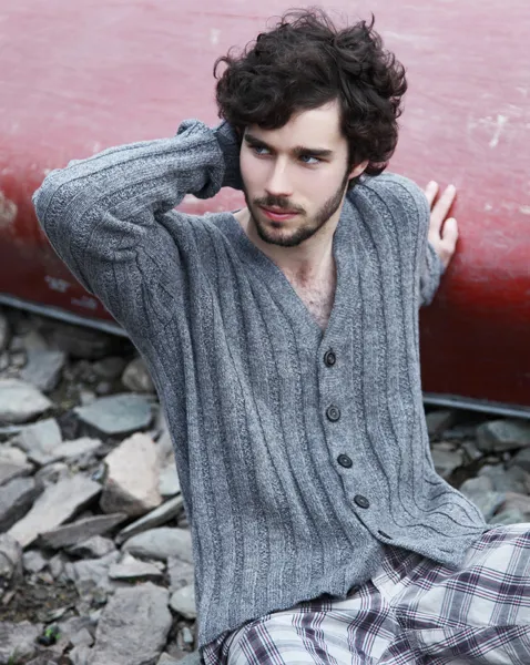 Ung mann sittende på bakken mot en rød vegg