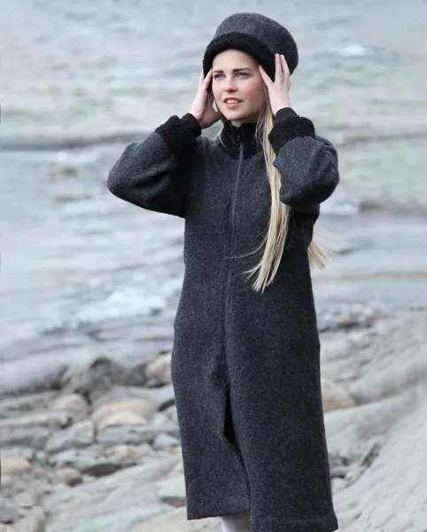 Ung kvnne i strandkanten ikledd mørk grå og sort kåpe