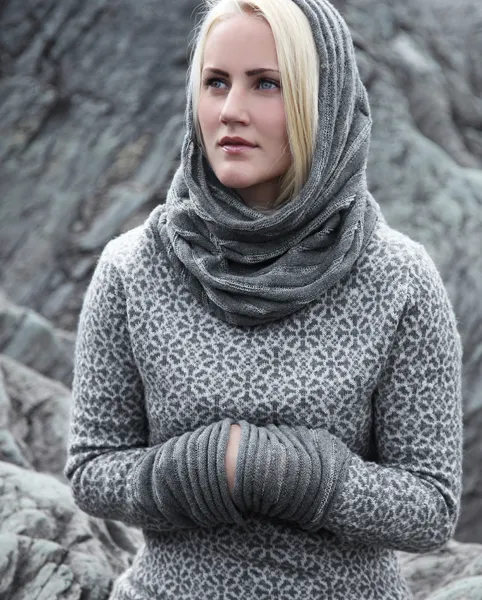 Ung kvinne ikledd ullgenser med små mølleliknende mønstre. Hals/skjerf delvis over hodet ig samme garn og uttrykk som de rause mansjettene